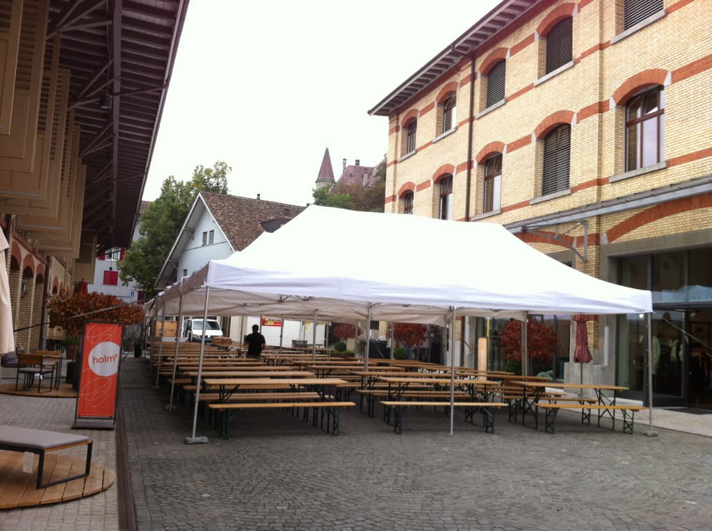 Faltpavillons mit Festbänken in einem Innenhof